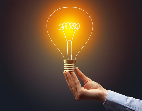 Hand holding light bulb on dark background, new idea concept