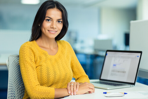 Portrait of a happy casual businesswoman in sweater sitting at her workplace in office-1